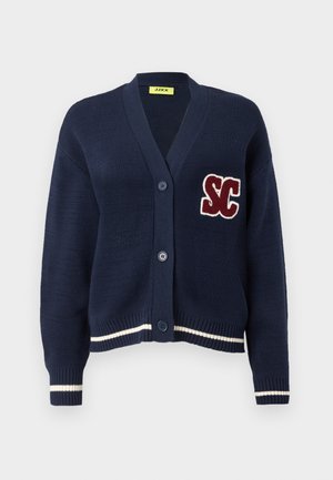 Námornícky pletený kardigán s v-výstrihom, s marhuľovou logom "SC", dvoma gombíkmi a bielymi pruhmi na leme a manžetách.