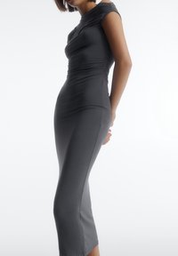 Robe grise ajustée à manches courtes, avec une texture froncée sur le corsage et un ourlet à hauteur du genou. Tissu lisse avec un éclat subtil.