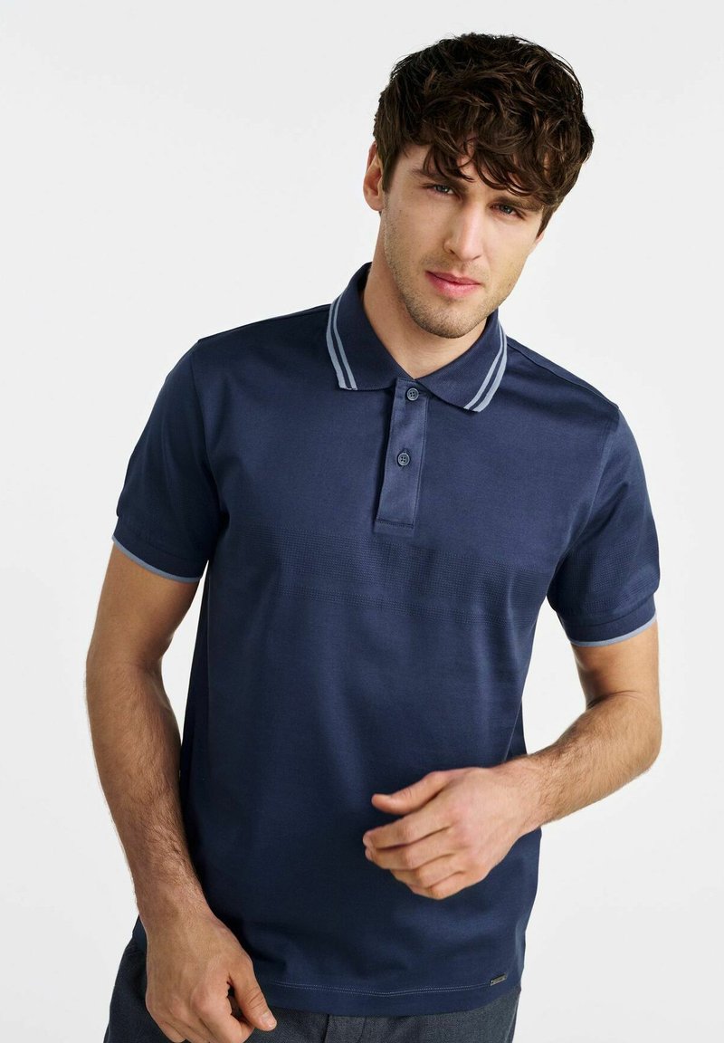 Granatowa koszulka polo z kołnierzykiem, z jasnoniebieskimi paskami, trzema guzikami i teksturowanymi poziomymi liniami na klatce piersiowej.