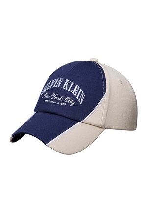 Dvojfarebná baseballová čiapka v námorníckej modrej a béžovej farbe s vyšitým bielym nápisom „Calvin Klein New York City“ na prednom paneli.