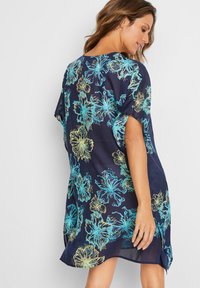 Abito rilassato blu navy con vivaci motivi floreali blu e gialli, maniche corte e spacco laterale per facilitare il movimento.