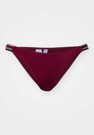 Bañador de bikini en color burdeos de algodón con una textura suave. Presenta una cinturilla delgada con la marca "Calvin Klein" y un diseño de corte clásico.