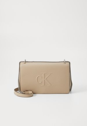 Beige suorakaiteenmuotoinen nahkainen crossbody-laukku, jossa on hopeinen ketjuhihna ja etuosassa kohokuvioitu "cK"-logo.