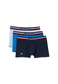 Pack de trois boxers : bleu clair, bleu et marine. Taille élastique avec le logo Lacoste et des rayures rouges et blanches. Matière en coton doux.