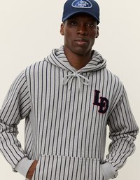 Pelēka svītrainā kapuce ar tumši zilu svītru, regulējams virknes kapuce, priekšējā kabata un izšūts sarkans emblēma uz krūtīm. Apvienota ar tumši zilu cepuri.