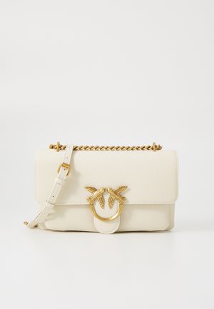 Kremasta kožna torba s teksturiranom površinom, lanac u zlatnoj boji i dekorativna kopča s dva motivi ptica.