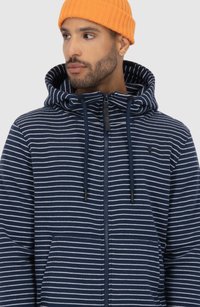 Felpa con zip frontale a righe navy, cappuccio con cordini e tasche laterali. Presenta una texture morbida e un design semplice e moderno.