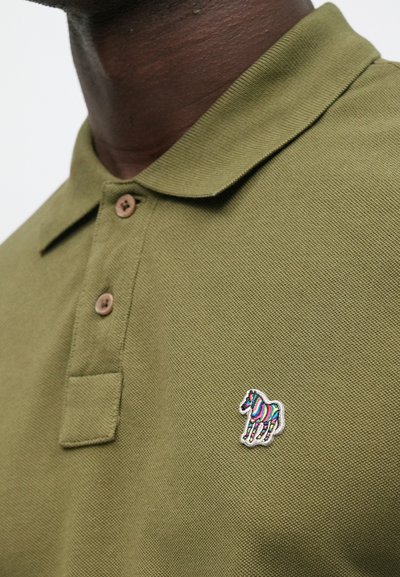 Olivzaļš polo krekls no teksturētas auduma, ar trīs pogu aizdares joslu un mazu krāsainu izšūtu zirga logo uz krūtīm.