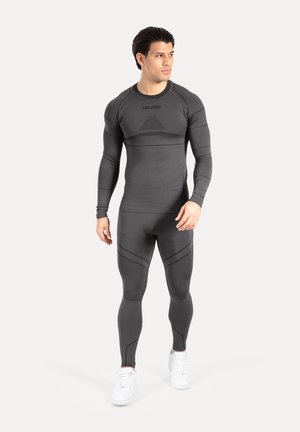 Traje deportivo negro hecho de material elástico y transpirable, con mangas largas ajustadas y piernas entalladas, que presenta detalles de patrones y detalles acanalados.