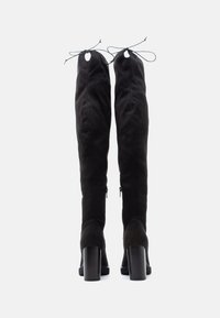 Melnas zamšādas pārceļošo zābaku ar bloku papēdi, ar auklu akcentiem augšpusē un sānu rāvējslēdzēju vieglai uzvilkšanai.