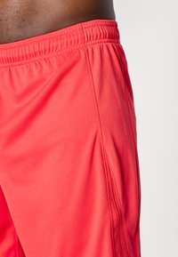 Røde atletiske shorts lavet af tekstureret, letvægtsstof. Har en elastisk talje med syninger og sideslids for bedre bevægelsesfrihed.