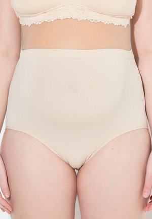 Beżowa, bezszwowa modelująca bielizna z wysokim stanem, noszona przez stojącą osobę ze swobodnie opuszczonymi ramionami, widoczna od talii do górnych partii ud.