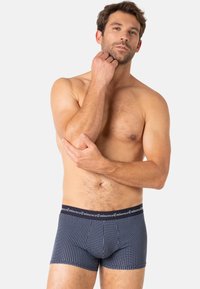 Boxer-briefs navy avec un motif texturé, une ceinture élastique portant le nom de la marque, et un design de poche profilée.