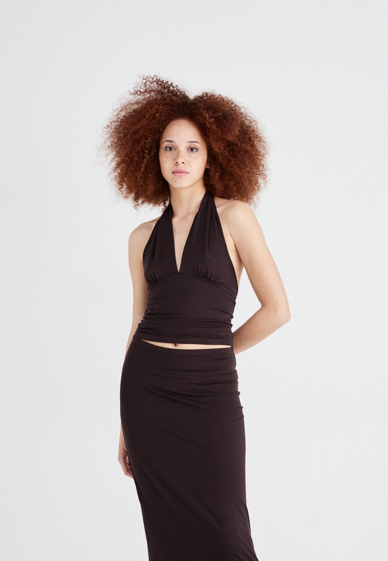 Top halter negru cu detalii strânse, asortat cu o fustă lungă. Material neted cu o siluetă ajustată. Design minimal.