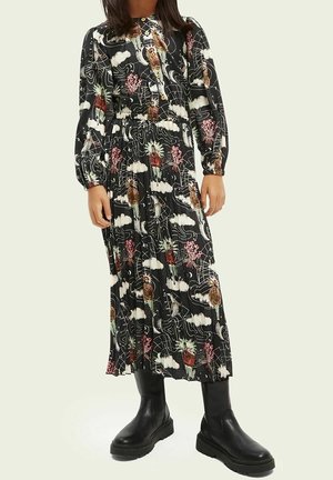 Vestido negro con mangas largas y un diseño floral en rosa, blanco y verde. Presenta un cierre de botones y un diseño plisado, combinado con botas negras.