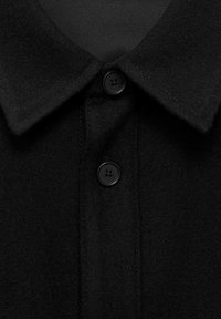 Black wool blend shirt with a collar, featuring a button closure and a soft texture. The fabric appears sturdy with a clean, tailored finish.