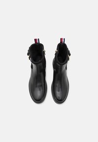 Bottines en cuir noir avec une finition lisse, fermeture éclair sur le côté et un tirant contrastant rouge, blanc et bleu à l'arrière.