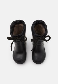 Bottes noires imperméables avec un extérieur lisse, doublure en fourrure douce et un revers en tissu froncé. Elles possèdent des lacets ronds et une semelle texturée.