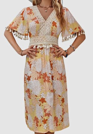 Vestido maxi floral con fondo amarillo, flores blancas y naranjas, escote en V profundo, bordes de encaje y borlas en las mangas y la cintura.
