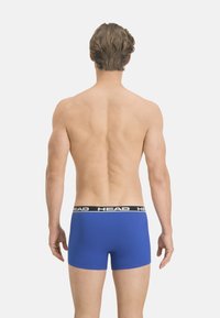 Boxer shorts bleus avec une ceinture élastique noire arborant le logo « HEAD » en blanc. Le tissu est lisse avec une coupe ajustée, présenté de dos.