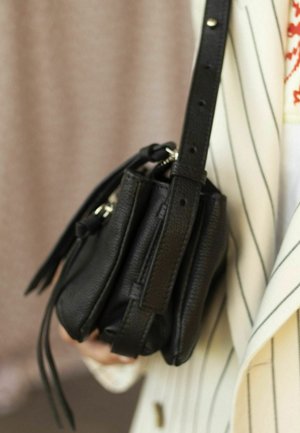 Borsa a tracolla nera in pelle con superficie texturizzata, cinturino regolabile e chiusura con zip. Presenta piccoli dettagli con nappine.