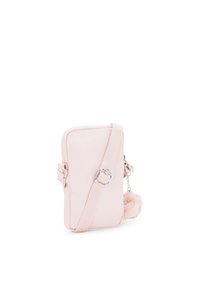 Malá růžová crossbody kabelka s hladkým povrchem, texturovaným popruhem a huňatým pom-pom přívěskem připevněným na zipu. Obdélníkový tvar.