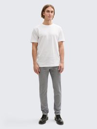 T-shirt branca em algodão, ajustada, com gola redonda; combinada com calças cinzentas texturizadas, corte slim, levando a sapatos pretos de atacadores.