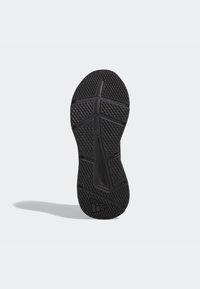 Suela de zapato de goma negra con superficie texturizada, que presenta un prominente diseño de chevrón y un logotipo de marca cerca del talón.