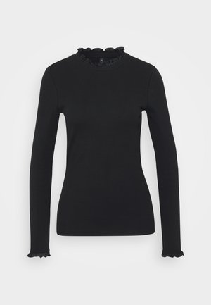 Svart langermet topp med ribbestruktur, med volangdetaljer ved halsen og mansjettene for ekstra preg. Klassisk tettsittende design.