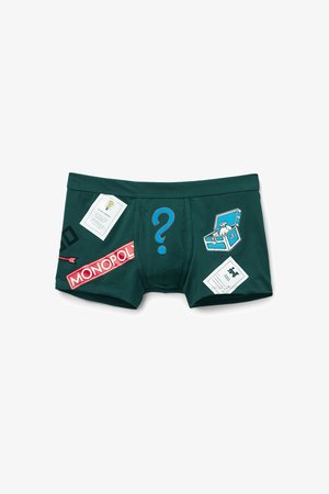 Grønne boxershorts lavet af bomuld med trykte designs, herunder Monopoly-branding, et spørgsmålstegn og flere legesyge grafik.