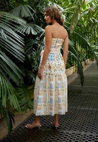 Stropeløs maxikjole med smocket bodice, prydet med et floral- og mønsterdesign i blå, gul og orange nuancer. Letvægtsstof.
