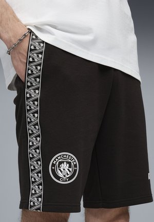 Pantaloni corti neri in cotone con un logo bianco che presenta una nave e una rosa, accentuati da una striscia laterale a fantasia.