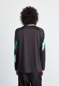 Zwart langemouwen T-shirt met mouwen in turquoiseaccenten, gemaakt van glad en licht materiaal. Heeft een ronde hals en een ontspannen pasvorm.