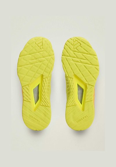 Bright yellow sneaker soles with a textured grip pattern, featuring a transparent window and brand name embossed. Distinctive design elements visible.