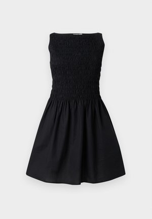 Rochie neagră fără mâneci, cu corset strâmt și decolteu smock și fustă evazată, expusă pe un fundal simplu și deschis la culoare.