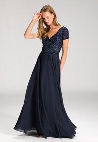 Robe bleu marine avec des manches courtes ornées, un décolleté en V et une jupe fluide, présentant des perles délicates sur le corsage.