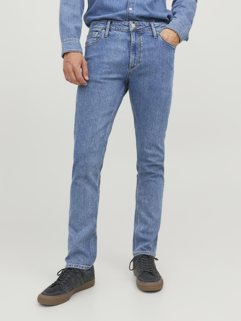 Jeans din denim albastru deschis, cu o croială slim, design clasic cu cinci buzunare și detalii de cusătură subtile. Purtați cu teniși negri.
