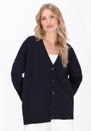 Marineblauwe cardigan van zacht gebreid materiaal. Voorzien van een diepe V-hals, knopen aan de voorkant en een relaxte pasvorm met lange mouwen en een ribgebreide zoom.