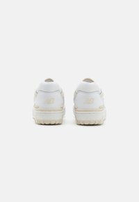 Sneaker bianche con finitura testurizzata, presentano un collo imbottito e una suola in gomma di tonalità neutra. La vista posteriore mostra il dettaglio del logo sul tallone.