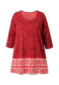 Rode tuniek met een bloemenpatroon in donkerdere tinten rood, met lange mouwen en een ronde hals. De onderste zoom heeft een contrasterende witte bloemenrand.
