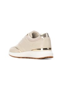 Zapatilla beige con acentos metálicos dorados, paneles texturizados y una suela media blanca. Presenta un talón acolchado y suela exterior de goma texturizada.