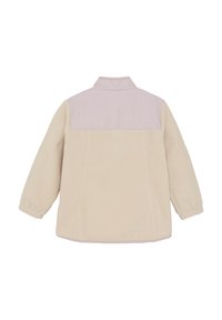 Fleece-Jacke in Creme mit einem helllila Schulterbereich. Verfügt über einen Kragen und elastische Ärmelbündchen. Weiche Textur, einfaches Design ohne sichtbare Hardware.