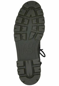 Schwarze Gummisohle mit einem robusten Profilmuster, das tiefe Rillen für besseren Halt aufweist. Zentrales Logo-Emblem und Schnürschlaufen-Details.