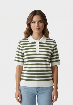 Femme aux cheveux châtain clair portant un polo à manches courtes rayé vert et blanc et un jean bleu clair, debout devant un fond blanc.