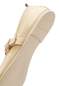 Zapato plano beige con parte superior de cuero suave, con un acento de hebilla en tono dorado y suela acolchada. Punta redondeada y diseño minimalista.