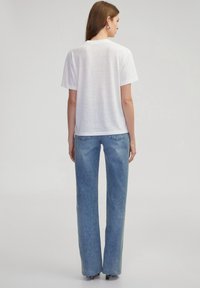 Witte T-shirt met korte mouwen, lichtgewicht stof, gecombineerd met lichtblauwe wijde jeans met rafelige hem en klassiek vijf-pocket ontwerp.