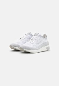 Zapatillas deportivas en blanco y gris con un upper de punto transpirable, patrones texturizados, cierre con cordones y una suela blanca moldeada.