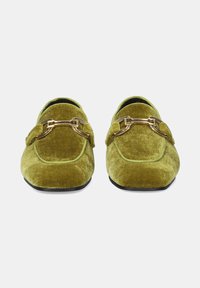 Par de mocasines de terciopelo verde oliva con detalle de hebilla de metal dorado, punta redonda y suelas negras sobre un fondo blanco sencillo.