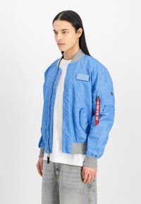 Svjetloplava bomber jakna od glatkog materijala, siva pletena ovratnik i manžete, prednji džepovi i zatvaranje na rajsferšlus; uključuje oznaku.