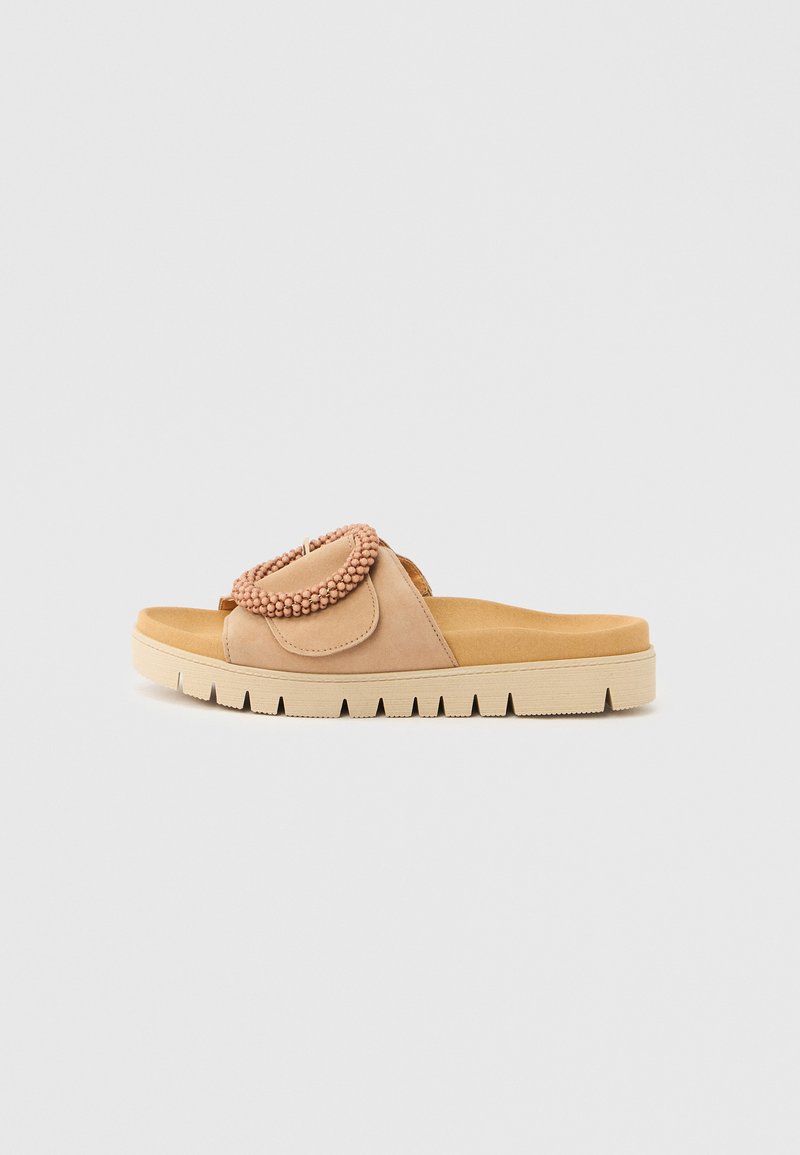 Beige Pantolette mit einer strukturierten Oberseite, die ein kreisförmiges Akzentdetail aus kleinen Perlen aufweist, und einer dicken, profilierten Sohle für besseren Halt.